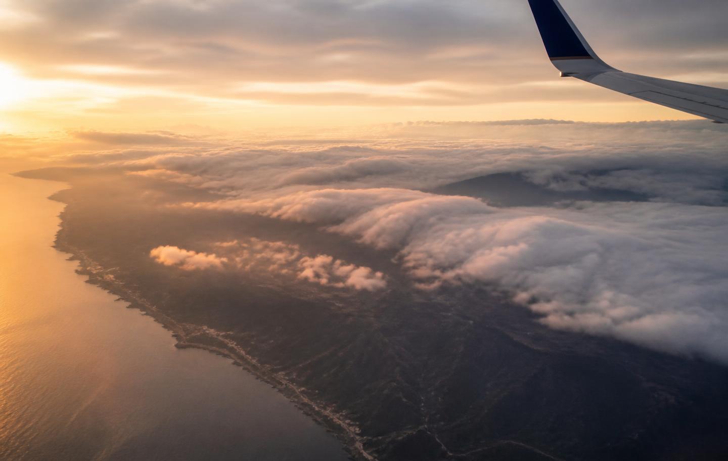 Aerial view of clouds and coastline from an airplane window